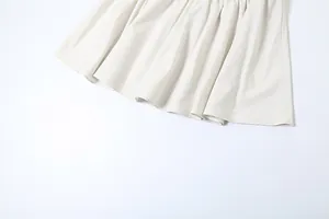 Close-up detail shot of the elegant off-white pleated hemline of a spring slim-fit dress