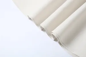 Macro view showing the pleated hem and fine stitching of a cream-colored elegant dress