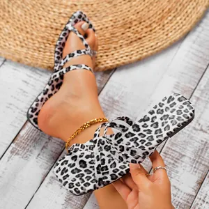 Trendy leopard print open-toe square toe flat sandals for women on a rustic wood floor