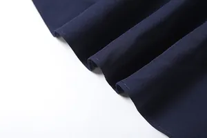 Macro detail of navy blue pleated dress hem showing fine stitching and fabric texture.