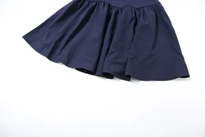 Macro detail of the pleated hemline texture on a navy blue slim-fit fashion dress