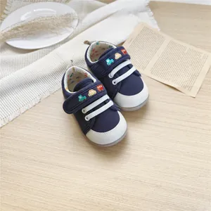 Detailed view of navy baby sneakers with cute car embroidery on soft wooden background