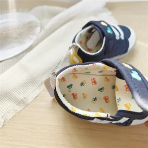 Close-up of baby walking shoes featuring colorful car embroidery and soft inner lining
