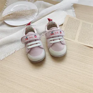 Detailed view of pink embroidered baby walking shoes with soft soles and velcro strap.