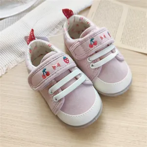 Detailed macro view of pink baby walking shoes with cute cherry and strawberry embroidery.