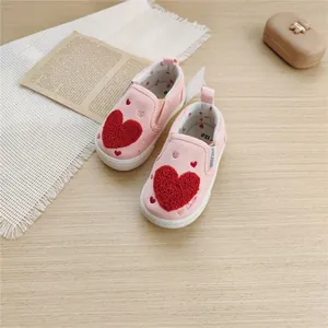Detail view of pink toddler canvas shoes featuring a plush red heart applique on top