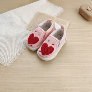 Close-up of pink children's canvas shoes featuring soft soles and a red heart design