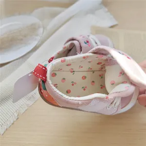 Close-up view of soft pink baby walking shoes with strawberry embroidery and velcro strap
