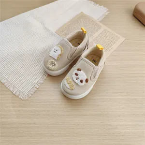 Detailed shot of beige canvas toddler shoes with cute panda and toast embroidery.