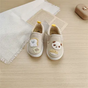 Close-up of children's beige canvas shoes with cute cartoon toast and panda embroidery