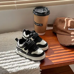 Primer plano de zapatillas infantiles en blanco y negro con velcro en mesa de madera