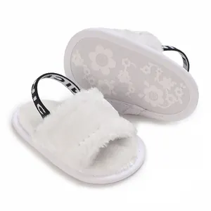 Gros plan de sandales blanches en peluche pour bébé avec semelle à fleurs et bride