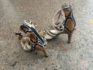 Detailed view of women's snakeskin strappy high heel sandals with back zipper closure.