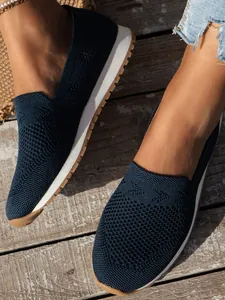 Nahaufnahme von dunkelblauen, atmungsaktiven Fly-Knit-Ballerinas auf Holzterrasse.