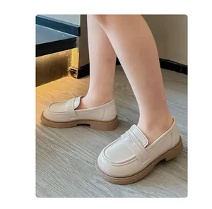 Nahaufnahme von beigen Slip-On-Loafers im britischen Stil für Kinder an den Füßen