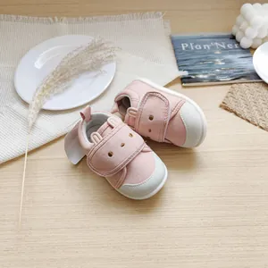 Gros plan de chaussures de marche roses pour bébé avec oreilles de lapin et velcro.