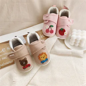 Close-up detail of adorable baby soft sole walking shoes with bear and lion embroidery.