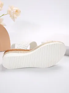 Detalle de sandalias de cuña blancas con suela de yute trenzada y base antideslizante