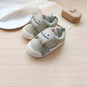 Vue détaillée de chaussures bébé dinosaure vert avec semelle souple et velcro.