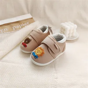 Detailed view of beige baby walking shoes featuring cute lion and bear embroidery designs