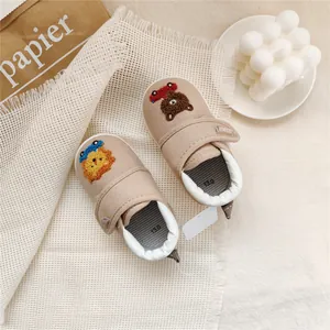 Detailed view of beige baby walking shoes with cute animal embroidery and velcro strap