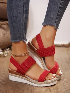 Detalle de cerca de sandalias de cuña rojas con tira trenzada y suela de plataforma texturizada