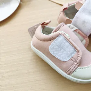 Gros plan d'une chaussure rose pour bébé avec tissu doux et bande velcro.