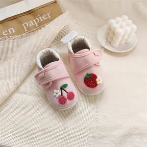 Close-up of pink baby walking shoes with embroidered strawberry and cherry motifs