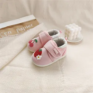 Close-up of pink baby walking shoes with strawberry and cherry embroidery details