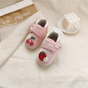 Close-up view of pink baby walker shoes with strawberry and cherry embroidery details