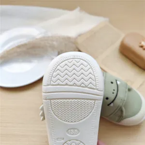 Gros plan de la semelle antidérapante et de la taille 13,5 sur chaussure bébé verte.