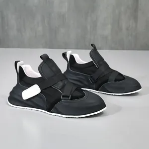 Moderne zwarte leren heren sneakers met dikke witte zolen en klittenbandsluiting.