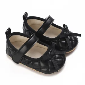 Primer plano de zapatos de bebé acolchados negros con un elegante detalle de lazo