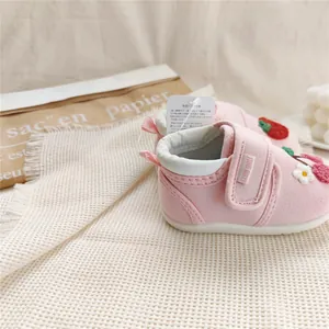 Close-up detail of pink embroidered baby walking shoes with soft soles and velcro