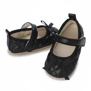 Detalle de zapatos negros acolchados para bebé niña con un lazo y correa elegantes