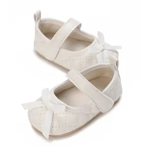 Detalle de zapatos blancos para bebé niña con patrón acolchado y lazo decorativo