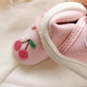 Detailed close-up of pink baby walking shoe with cute cherry embroidery