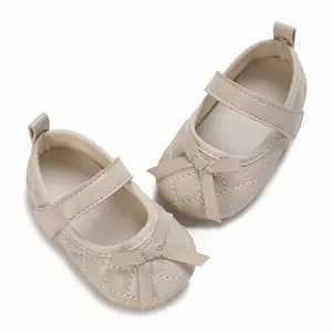 Primer plano de zapatos beige acolchados para bebé niña con suela blanda y lazo decorativo.