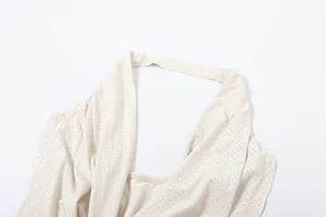 Détail d'une robe licou beige ornée de strass argentés scintillants de haute qualité.