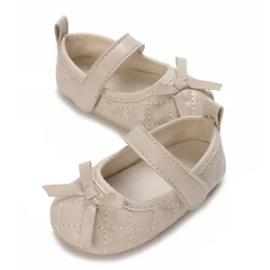 Primer plano de zapatos Mary Jane beige para bebé con patrón acolchado y un lazo