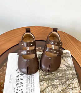 Detalle de zapatos Tabi de cuero marrón para bebé con doble cierre y costura blanca.
