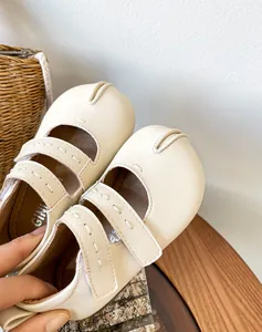 Primer plano de merceditas de cuero crema para bebé con el icónico diseño Tabi