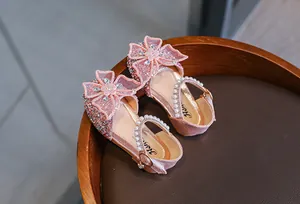 Close-up shot of elegant pink glittery girls' princess sandals with mesh bowknot and pearls