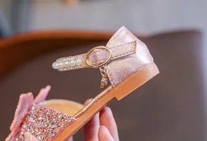 Close-up of pink glitter girl's sandal with pearl strap and golden buckle for summer.