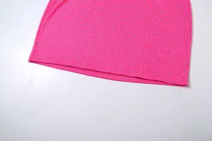 Gros plan sur l'ourlet orné de strass étincelants d'une robe moulante de couleur rose vif