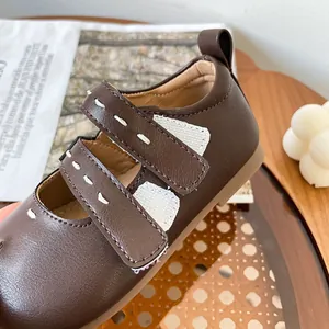 Clásicos zapatos de caminante marrones para bebé niña con costuras blancas y velcro.