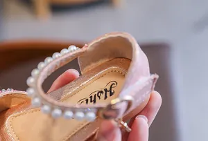 Macro view of pink girls' sandals featuring elegant pearl straps and soft sparkling finish