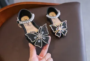 Detail view of black girl's princess sandals with rhinestone butterfly and pearl strap