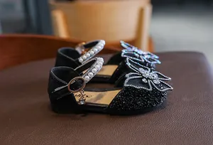 Close-up of black girl's princess shoes with rhinestone butterfly bows and pearl straps
