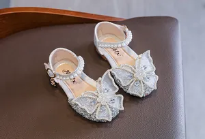 Close-up of sparkling silver girls' princess shoes with large butterfly and pearls